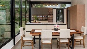 A modern kitchen with a central island, white cabinetry, and a dining area with a wooden table and chairs. - Casa completa dentro de un complejo privado con seguridad 24/7 (La Libertad)