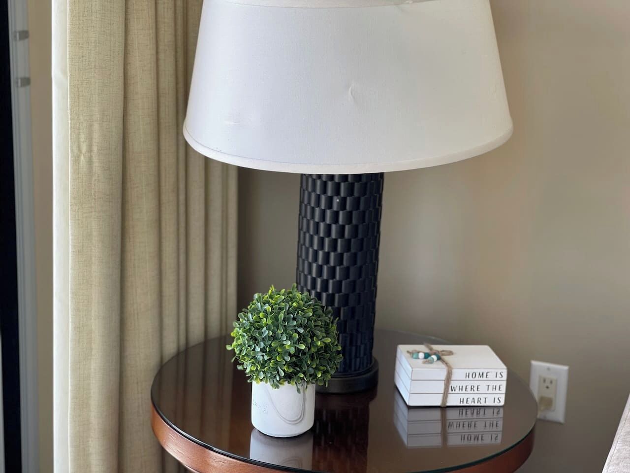 A lamp, a small potted plant, and a stack of books on a round table.