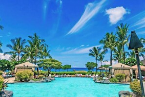 A resort with a large pool, palm trees, and beach views.