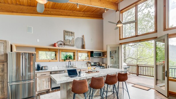 A spacious kitchen with a large island, wooden cabinets, and a view of the outdoors. - Lake Life Mountain & Lake Views, Hot Tub, & Dock (Butler)