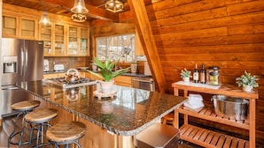 A kitchen with wooden walls, granite countertops, stainless steel appliances, and bar stools.