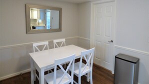 A dining area with a white table and chairs, a mirror on the wall, and a white door. - ***Remodeled Altadena Town Home*** Fabulous Location! (Birmingham)