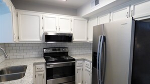 A kitchen with white cabinets, stainless steel appliances, a microwave, oven, and refrigerator. - ***Remodeled Altadena Town Home*** Fabulous Location! (Birmingham)