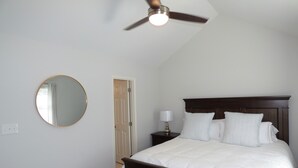 A bedroom with a bed, a round mirror, a ceiling fan, a nightstand with a lamp, and a door. - ***Remodeled Altadena Town Home*** Fabulous Location! (Birmingham)