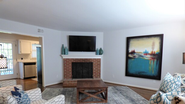 A living room with a fireplace, a television mounted above it, and a large painting on the wall. - ***Remodeled Altadena Town Home*** Fabulous Location! (Birmingham)