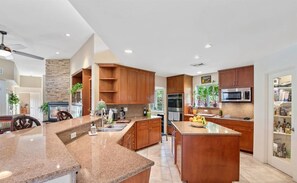 A modern kitchen with granite countertops, wooden cabinets, and a central island.