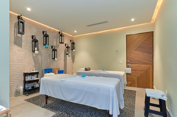 A room with two beds, a wooden door, and wall-mounted lanterns.