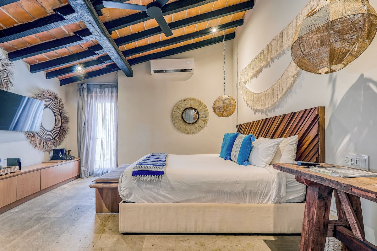 A bedroom with a large bed, wooden headboard, and a ceiling fan.