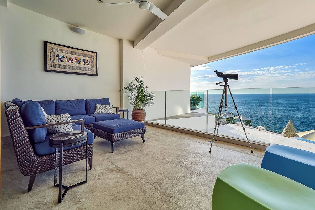 A balcony with a telescope, a sofa, and a potted plant.
