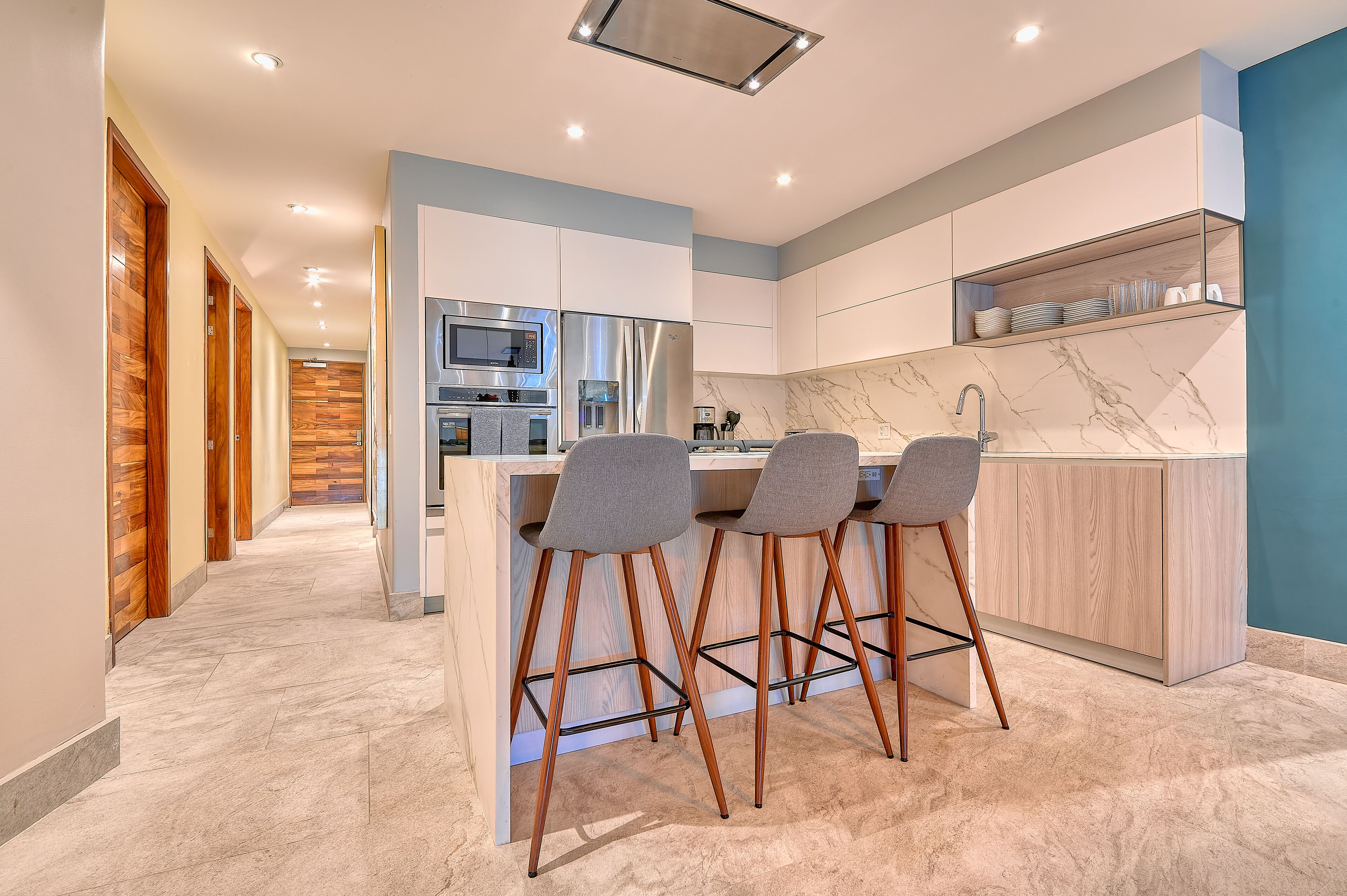 Una cocina moderna con una isla central, taburetes de bar y electrodomésticos integrados.