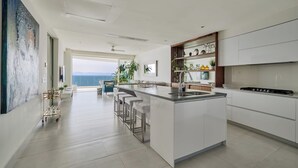 Una cocina moderna con una isla central, taburetes de bar y vistas al exterior.