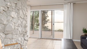 Un ampio balcone con parete in pietra, porta scorrevole in vetro, una panca e un divano.