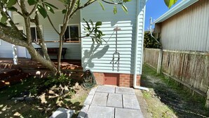 Ein Haus mit Ziegelterrasse, Holzzaun und Baum.