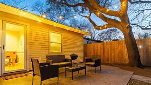 Une terrasse avec une table et des chaises, une clôture en bois et un arbre.