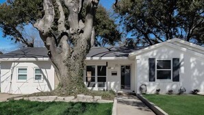 Une maison de plain-pied avec un grand arbre dans le jardin.