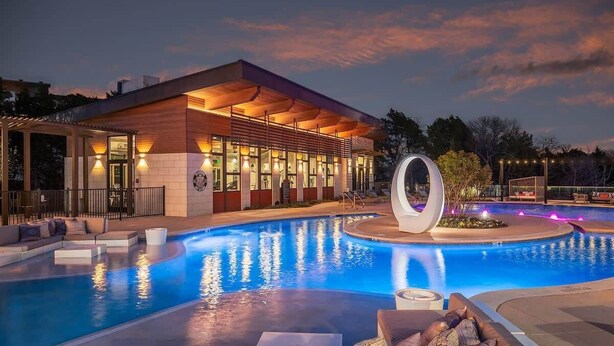 Un hotel moderno con piscina, area relax all'aperto e una caratteristica fontana circolare.