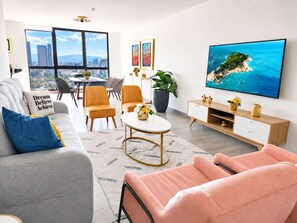 A modern living room with a sofa, chairs, a coffee table, and a TV displaying a scenic view.
