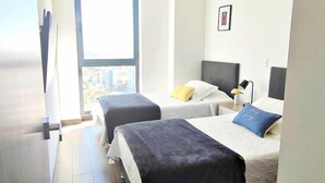 Une chambre d’hôtel avec deux lits, une grande fenêtre et une vue sur la ville.
