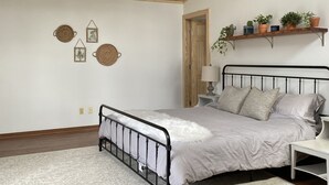 A bedroom with a bed, a ceiling fan, a wooden ceiling, a white wall, and a shelf with potted plants. - Spacious kid-friendly chalet minutes to Boone, Blowing Rock, Blue Ridge Pkwy (Boone)