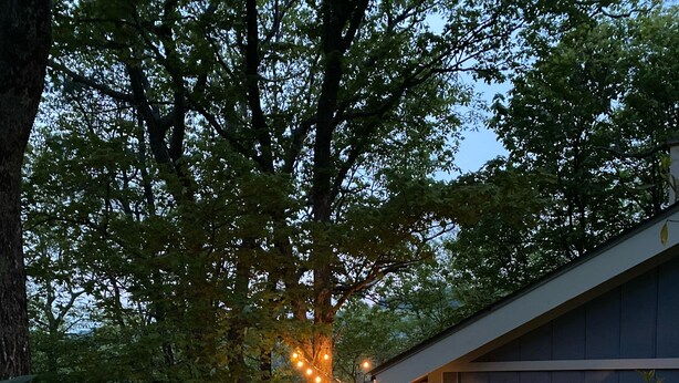 A wooden deck with outdoor furniture, a small dog, and string lights. - Spacious kid-friendly chalet minutes to Boone, Blowing Rock, Blue Ridge Pkwy (Boone)