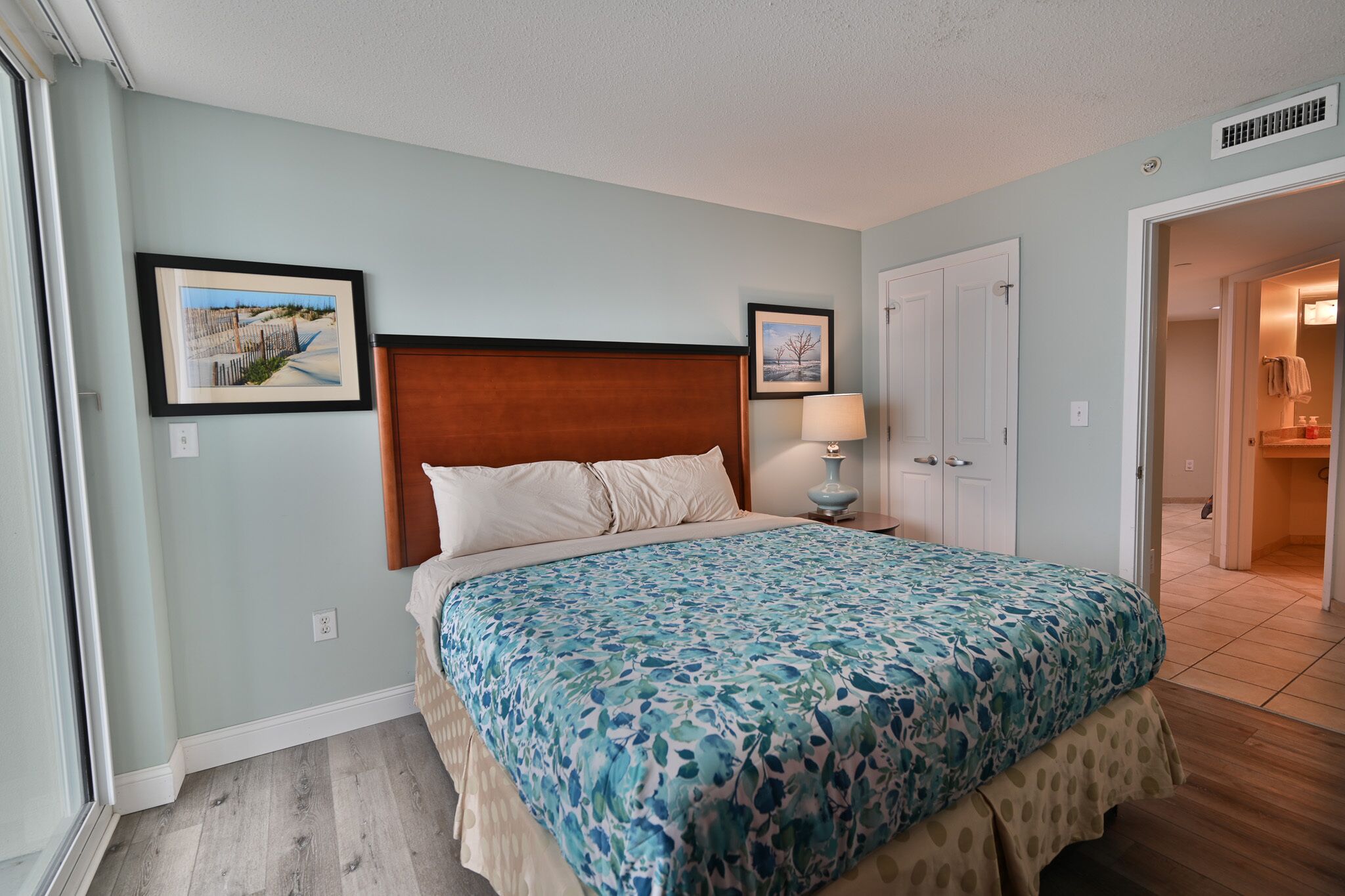 A bedroom with a bed, a nightstand, a lamp, and two framed pictures on the wall.