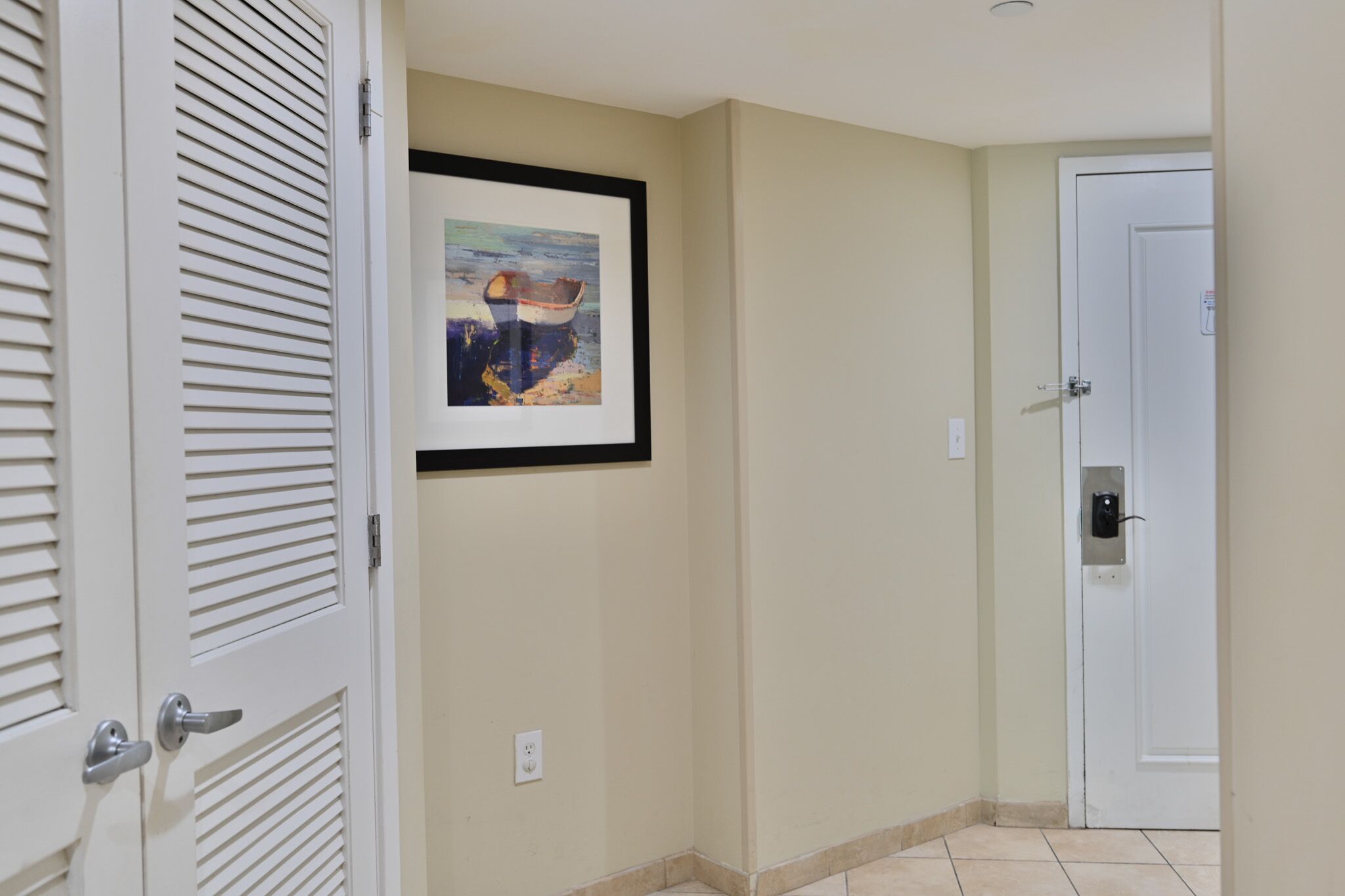 A hallway with a white door, a framed painting, and a security camera.