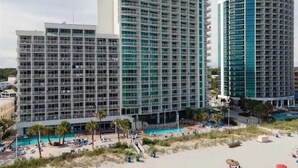 Un hôtel comprenant plusieurs immeubles de grande hauteur, un espace piscine et des installations de loisirs en bord de mer.