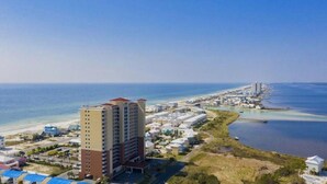 Un hotel frente al mar con varias construcciones, una playa y un puerto deportivo.