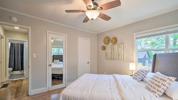 A bedroom with a large bed, a ceiling fan, a window with blinds, and a door leading to a bathroom. - Updated Fayetteville Home < 2 Miles to UArk! (Fayetteville)
