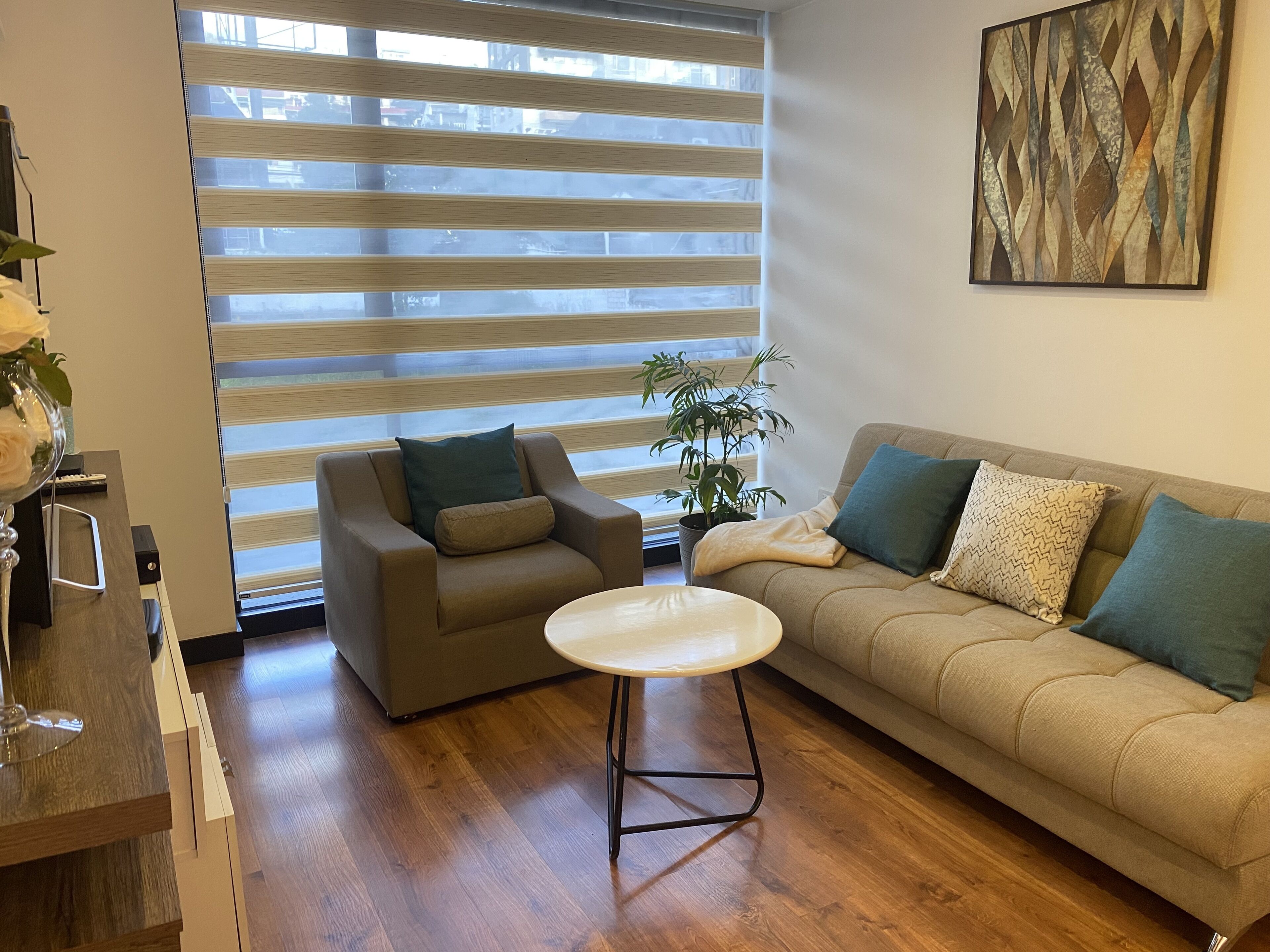 Una sala de estar con sofá, sillón, mesa de centro y una planta en maceta.