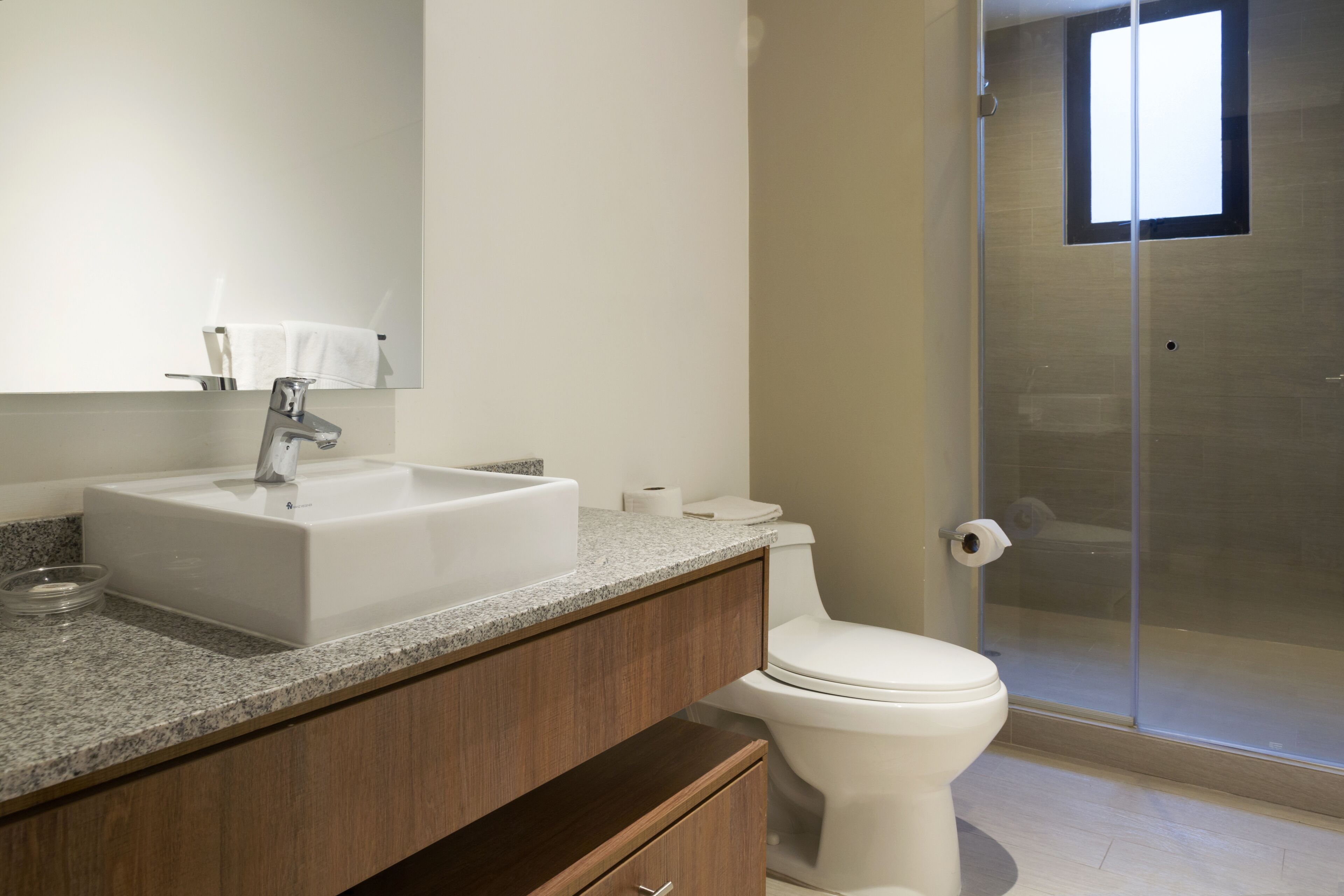 Een moderne badkamer met een witte wastafel, spiegel en toilet.