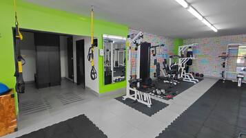 A gym with various exercise equipment, including a squat rack, benches, and weights.