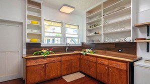 A kitchen with wooden cabinets, a built-in oven, and a window with a view of the outside. - 500 Feet to the Ocean!  (Koloa)