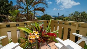A balcony with white chairs, a glass table, and a vase with flowers. - 500 Feet to the Ocean!  (Koloa)