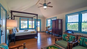 A spacious room with a four-poster bed, a ceiling fan, and large windows offering a view of the outdoors. - 500 Feet to the Ocean!  (Koloa)