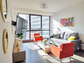 Un salon moderne comprenant un canapé, deux fauteuils, une table basse et un téléviseur.