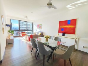 Un salon moderne avec un coin repas, de grandes fenêtres et une vue sur la ville.