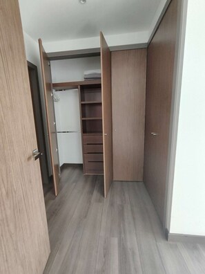 Un dressing avec des portes en bois, une armoire blanche et une étagère.