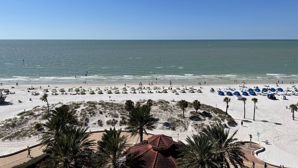 A beach with umbrellas and palm trees. - Lovely renovated condo with water views, great value for outstanding amenities (Clearwater Beach)