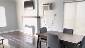 A modern dining area with a wooden table and chairs, a flat-screen TV mounted on the wall, and an air conditioning unit. - Remodeled rental in the heart of West Hollywood WeHo  (West Hollywood)