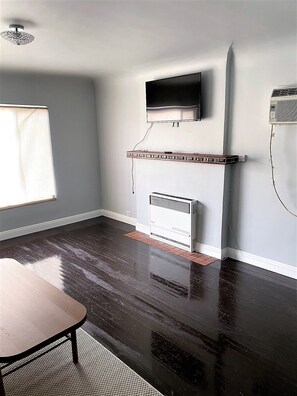 Cozy retreat with a mounted TV, white radiator, and a table, set against a clean, minimalist backdrop.