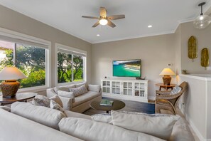 A living room with a sofa, a coffee table, a TV, and a ceiling fan.