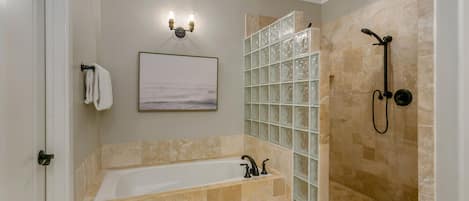 A bathroom with a bathtub, shower, and glass-enclosed shower area.