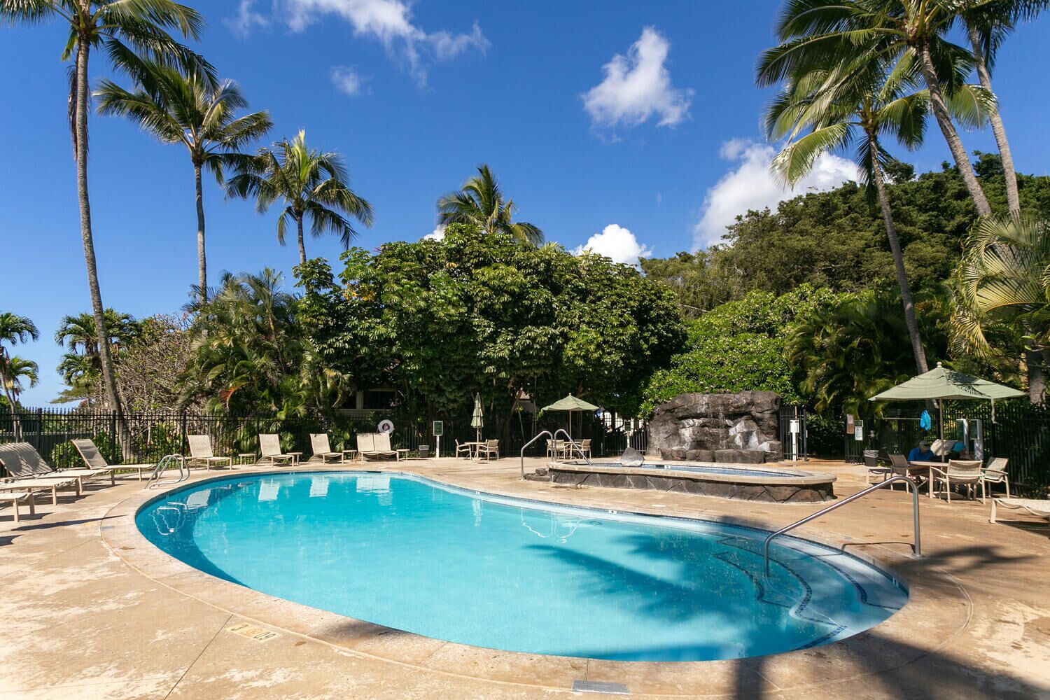A swimming pool surrounded by palm trees and lounge chairs.