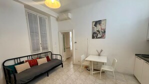 Un espacio habitable compacto con sofá, una pequeña mesa de comedor y una zona de cocina.