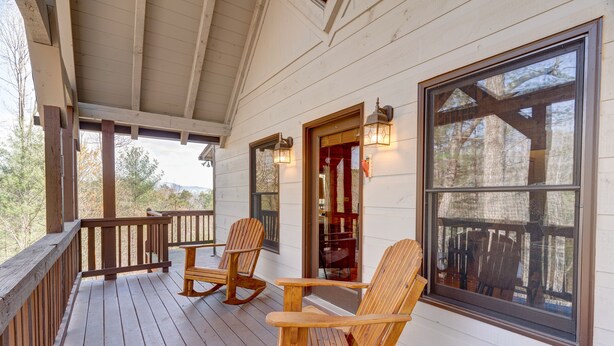 A wooden porch with rocking chairs and a large window. - Honeysuckle Hideaway: Mountain View Leisure Lodge (Ellijay)