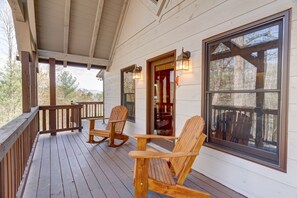 A wooden porch with rocking chairs and a large window.