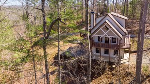 A cabin with a balcony, surrounded by trees and a rocky landscape. - Honeysuckle Hideaway: Mountain View Leisure Lodge (Ellijay)