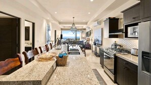 A modern kitchen with granite countertops, dark cabinetry, and stainless steel appliances. - Oceanfront Condo at the Copala (Cabo San Lucas)