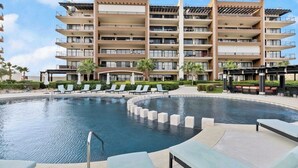 A multi-story hotel with a pool area featuring sun loungers and a water feature. - Oceanfront Condo at the Copala (Cabo San Lucas)
